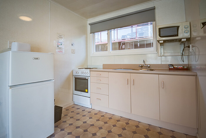 Kitchen with fridge, microwave and stove in the Two-bedroom retro unit at Red Tussock motel.